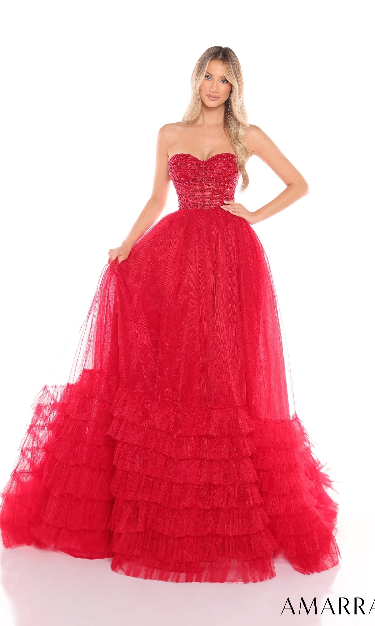 A woman stands against a white background wearing the Strapless Prom Ball Gown: Amarra 88277, featuring a sweetheart neckline, tulle fabric, and an elegant floor-length a-line ruffled skirt.